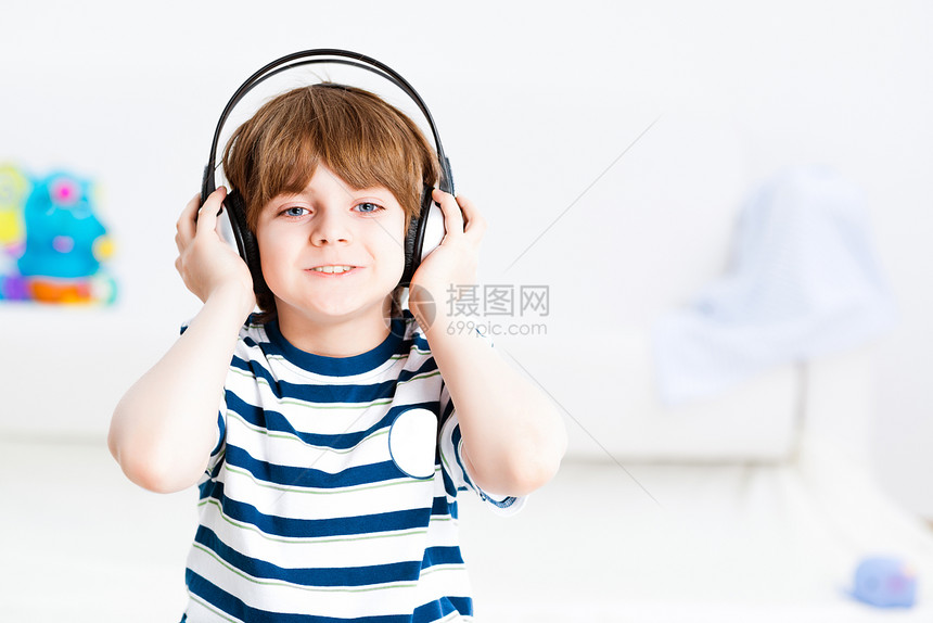 男孩听音乐辉煌微笑享受乐趣男性衣服耳朵娱乐耳机闲暇图片