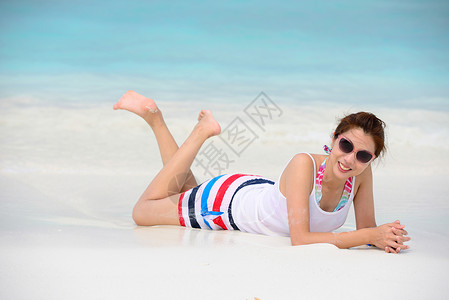 躺在沙滩上微笑的美女躺在沙滩上背景图片