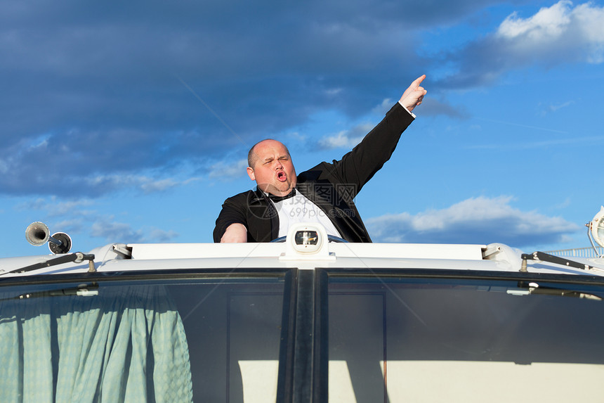穿燕尾服的超重人 在游艇上掌舵胖子天空套装男人奢华成人蓝色黑色甲板图片