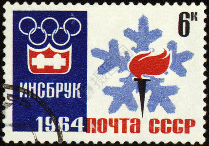 奥运会图片邮票上的奥林匹克火炬和徽章背景