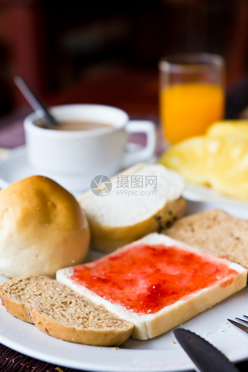 咖啡 面包和果汁 在餐桌上的盘子上图片