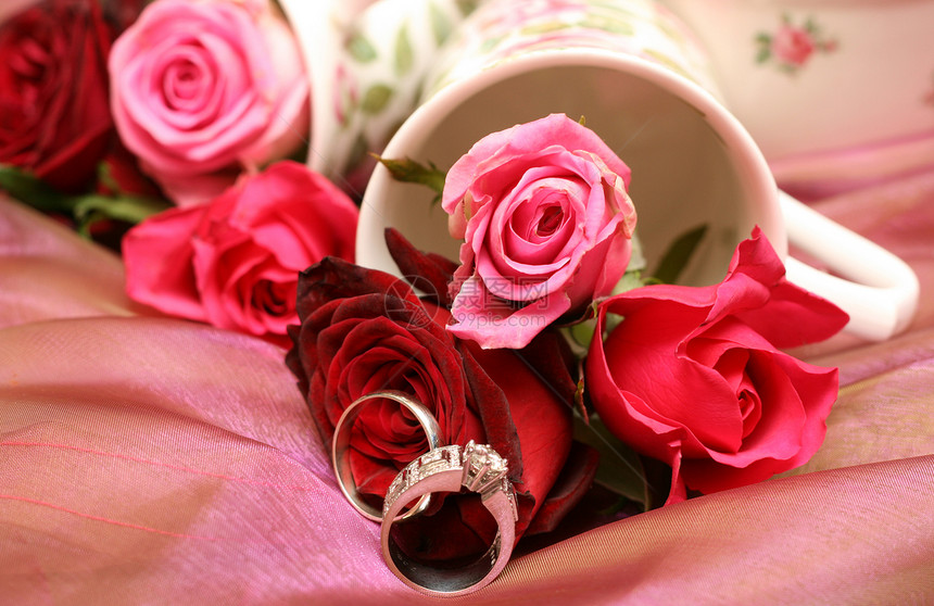 带结婚戒指的玫瑰花团石头金子宏观纸牌钻石花瓶玫瑰奢华夫妻丝绸图片