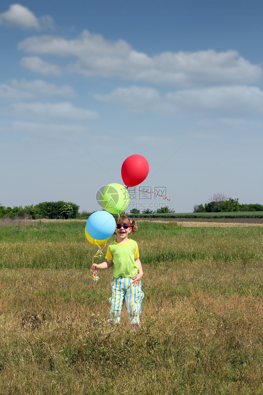 快乐的小女孩 在草地上沾满多彩气球图片