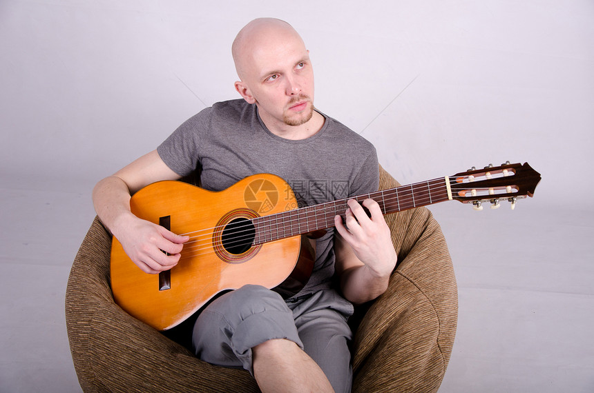 拿着吉他光秃秃的好人演员工作室男人乐器音乐家摇杆男性星星牛仔裤玩家图片