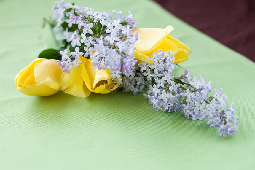躺在绿桌布上的春花的包束郁金香说谎紫色香味植物群绿色黄色惊喜庆典礼物图片