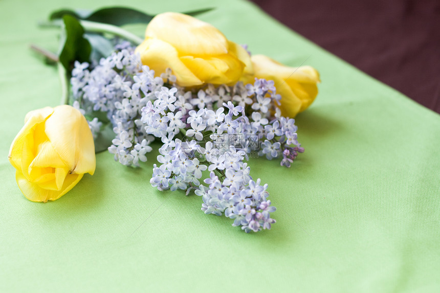 躺在绿桌布上的春花的包束紫色说谎惊喜香味庆典郁金香黄色绿色植物群礼物图片