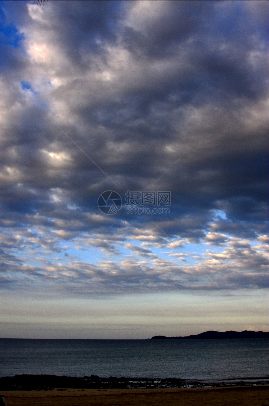 热带多云的山丘环礁湖天空浅蓝色波浪海岸线植物蓝色假期航行衬套岩石图片