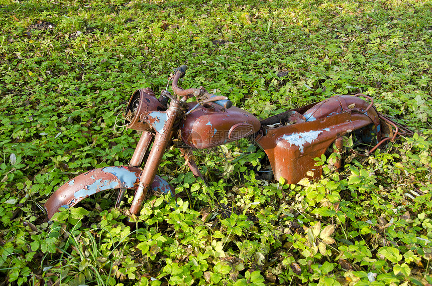 在草地上老旧和破碎的摩托车图片