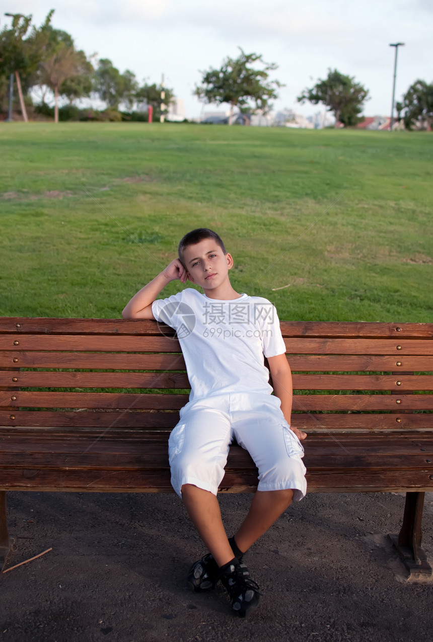 坐在公园的长椅上 可爱的男生在放松青少年孩子乐趣旅行男性天空农村微笑图片