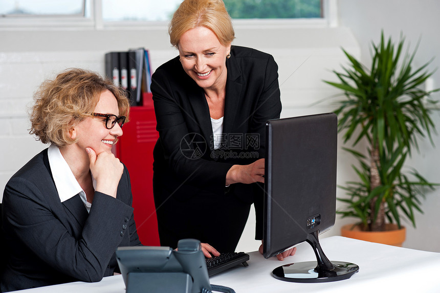 两位在任的公司妇女高兴雇主屏幕商界专家经理微笑沟通快乐办公室电脑图片