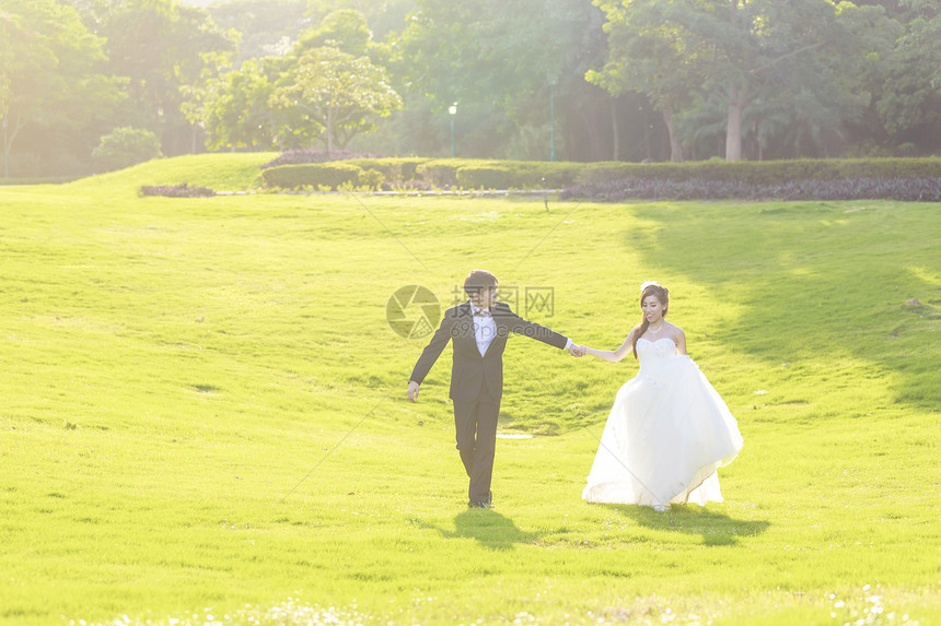 新娘和新郎步行太阳女士男性乐趣花束公园拥抱花朵男人婚礼图片