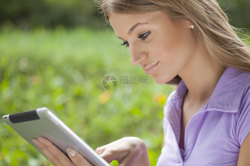 在公园使用平板电脑的妇女笔记本沟通导航药片技术绿色电子书触摸屏微笑成人图片