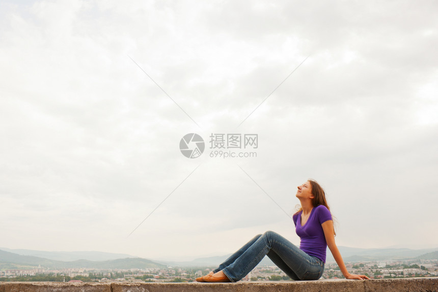 坐在户外与蓝天对面的年轻女子图片