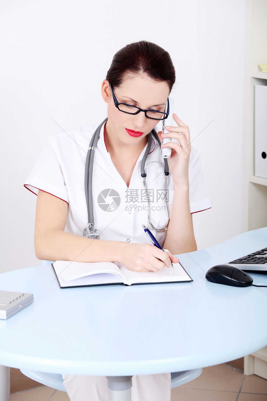 女医生通过电话和写作交谈眼镜办公室卫生工作室职场医师专家女士药品女性图片