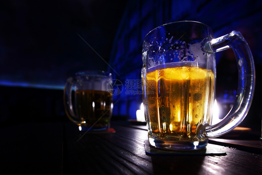 在黑暗中的啤酒金子泡沫火焰气泡琥珀色餐厅反射酒精庆典派对图片