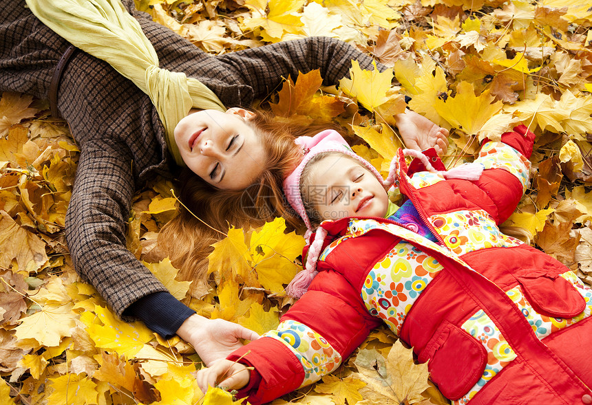 秋天黄色公园的母亲和女儿橙子夹克金发长发女孩后代季节背景叶子孩子图片