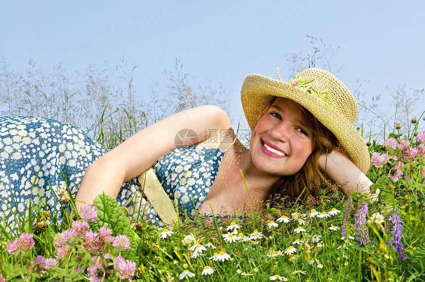 年轻女孩躺在草地上天空稻草公园场地女性青少年花朵野花享受微笑图片