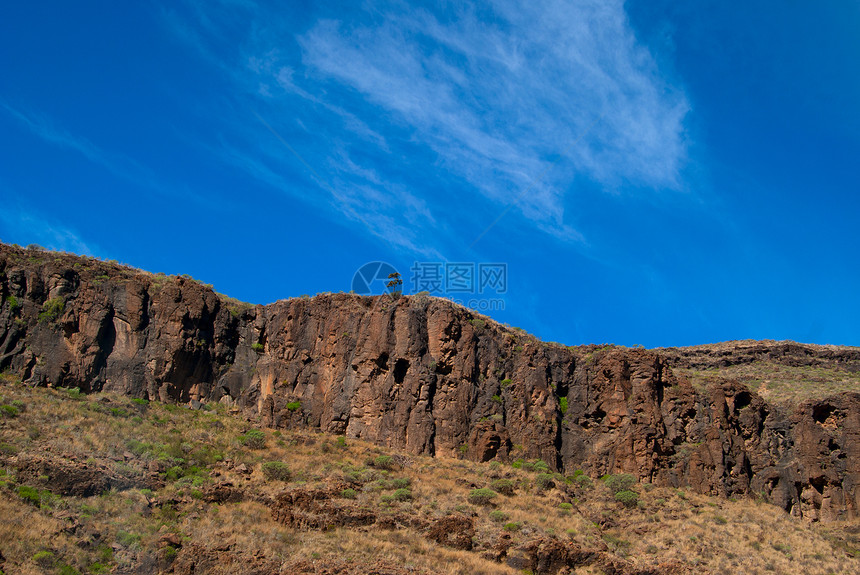 视图是蓝色天空顶峰时的孤树景色山峰场地场景岩石绿色骨折首脑孤独草地图片