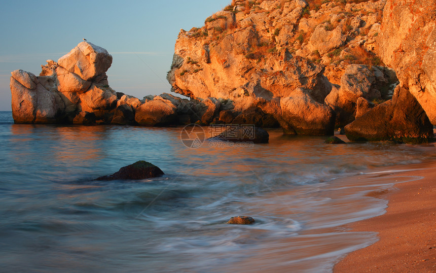 海滨 日落背景有岩石的海边图片