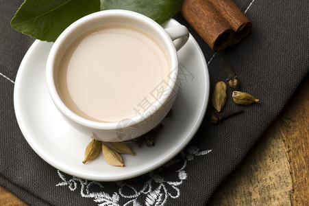 马萨拉沙伊泡茶小豆蔻叶子牛奶时间茶杯树叶红茶香料粉红色背景图片