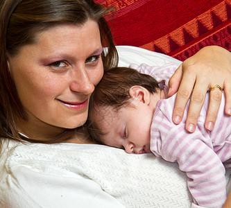 母亲拥抱婴儿入睡家庭尿布孩子微笑粉色甜蜜父母背景图片