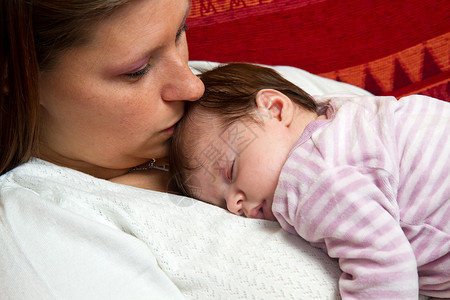 母亲亲吻睡觉的婴儿背景图片