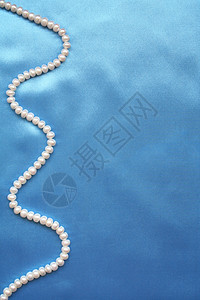光滑优雅蓝丝绸上的珍珠作为背景奢华蓝色投标折痕生产织物寝具材料新娘版税背景图片