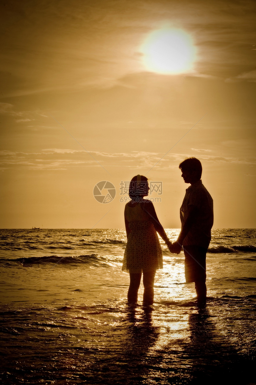 日落在海滩上的情侣浪漫的场景图片