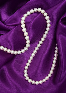 丝绸上的白珍珠白色手镯礼物宝藏黑色细绳展示紫丁香女性化光泽度背景图片
