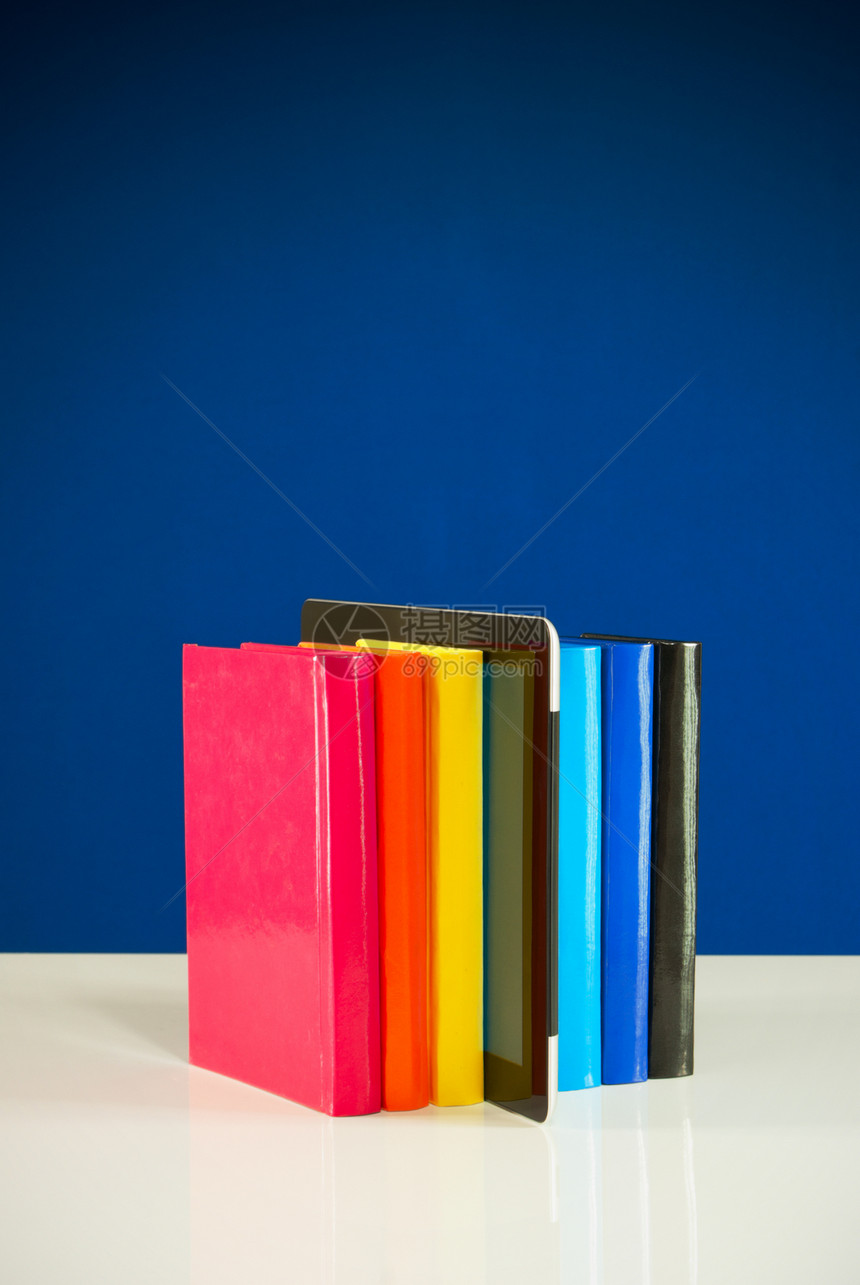 蓝色背景的彩色书籍和平板电脑行图片