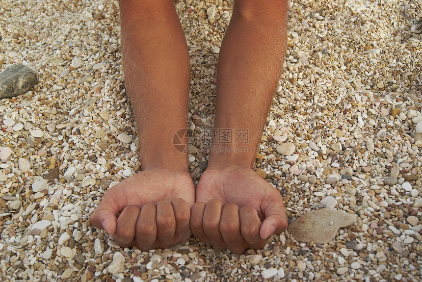 在背景石滩上将人晒黑的手压缩成摄像头图片