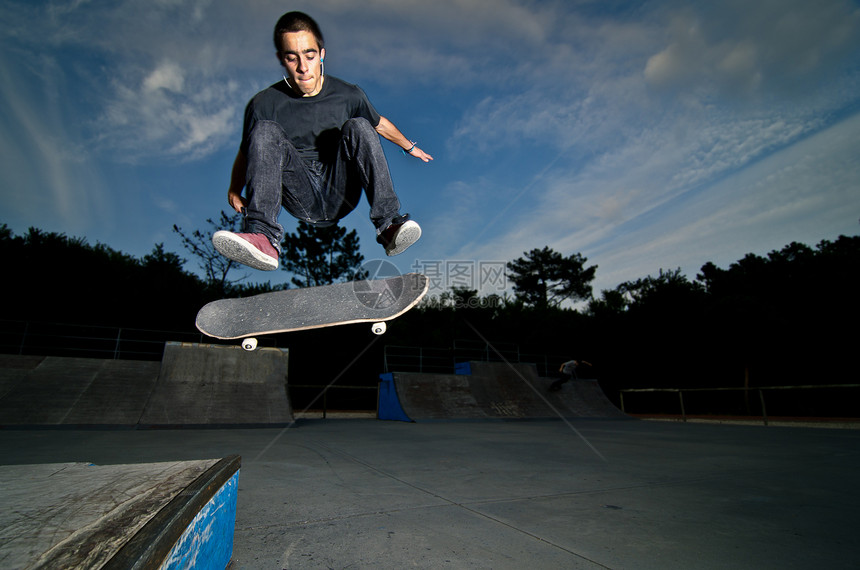 滑板机玩翻转把戏蓝色活力木头岩石溜冰者轮子滑板危险活动青年图片