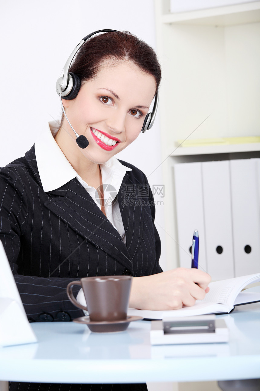 戴耳机的女商务人士桌子工人办公室工作写作人士电话职场商业成功图片