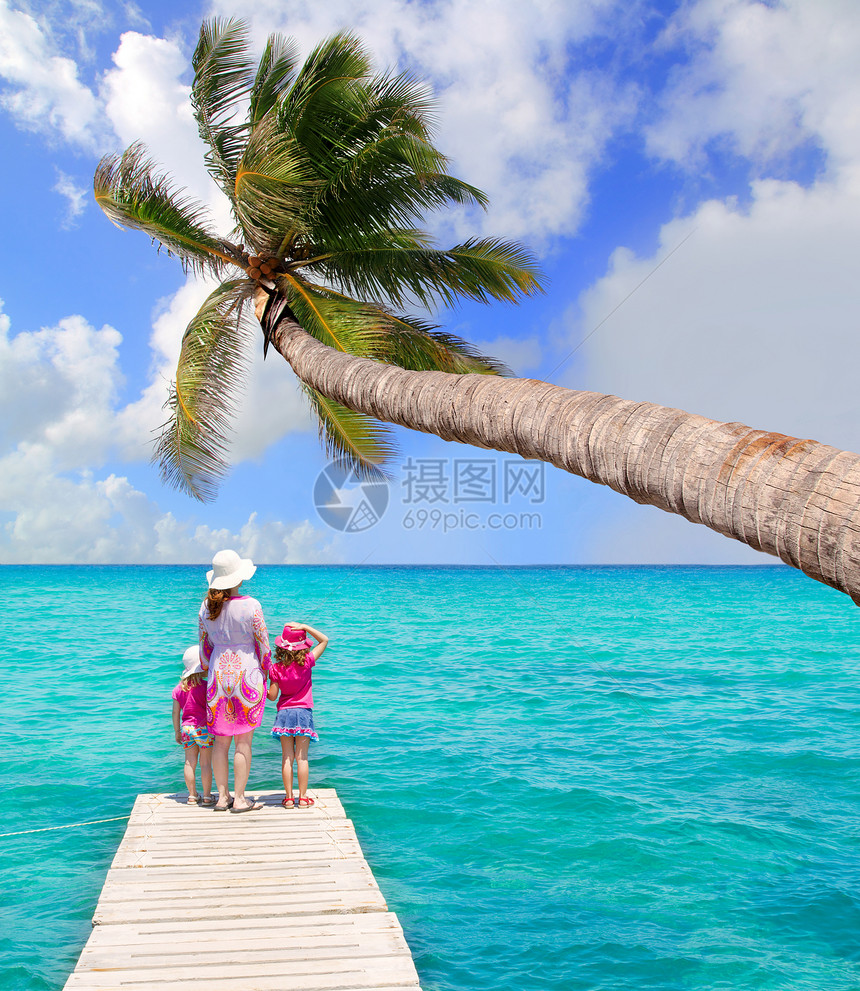 女儿和母亲在热带海滩的码头闲暇女儿们姐妹棕榈帽子童年蓝色女孩支撑女性图片
