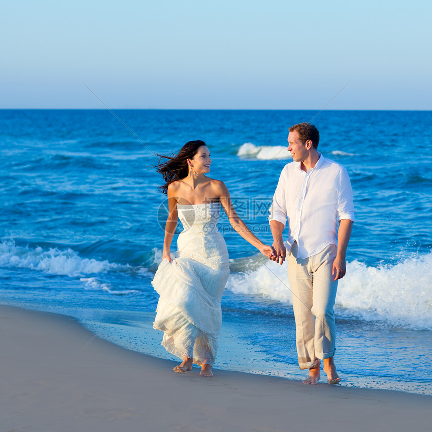 地中海夫妇在蓝色海滩上行走波浪裙子幸福海洋男性夫妻庆典情感假期女士图片