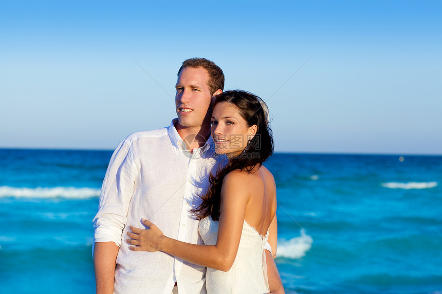 在蓝海度假中 情侣相爱的拥抱幸福婚礼假期新娘天空裙子波浪女性男性海洋图片