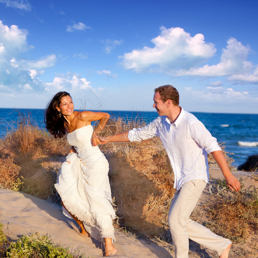 情侣在海滩上奔跑男性婚姻假期女性天空丈夫恋人女孩夫妻女士图片