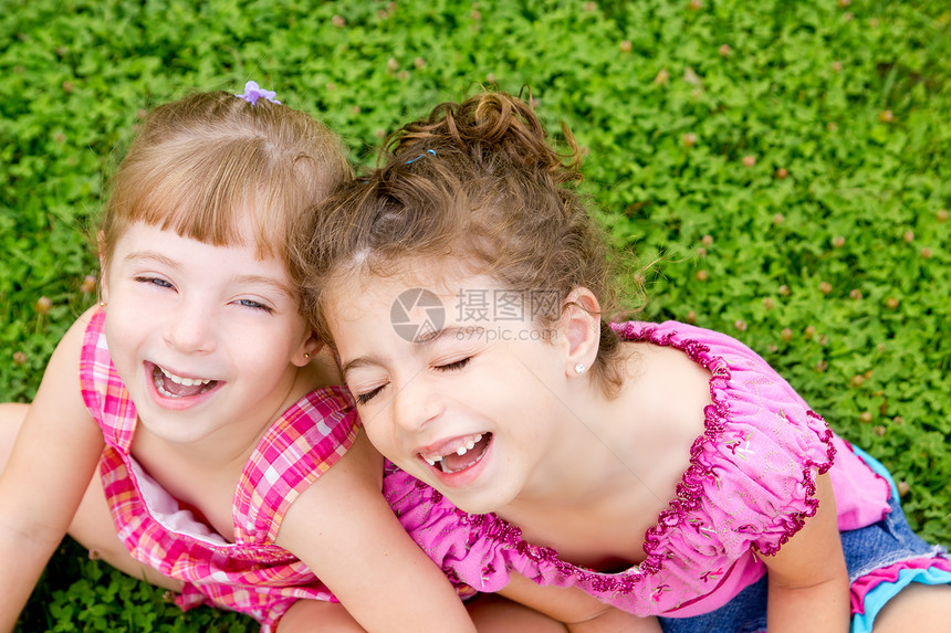 女孩笑着坐在绿草上童年假期恶作剧场地秘密快乐孩子们女儿们花园家庭图片