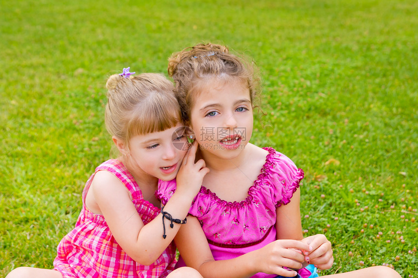 有两个姐妹女孩在草地上快乐秘密场地拥抱孩子们孩子假期女性诡计幸福恶作剧图片
