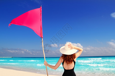 握着红沙滩旗杆的后方妇女背景图片