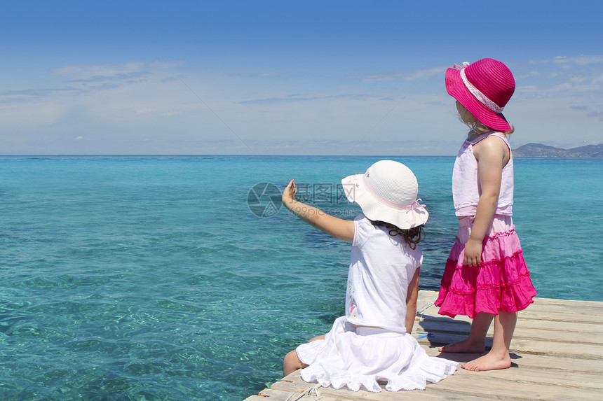 两个女孩 游览绿绿海 告别手势女孩孩子海岸蓝色帽子乐趣支撑游客女儿岛屿图片