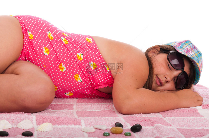 穿着泳装的女孩睡在海滩上石头游泳运动闲暇帽子鹅卵石黑发青少年活动女性图片
