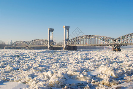 在阳光明媚的天气下 在冰冻河流上架桥蓝色漂移运输铁路季节雪景照片天空历史性建筑学背景图片