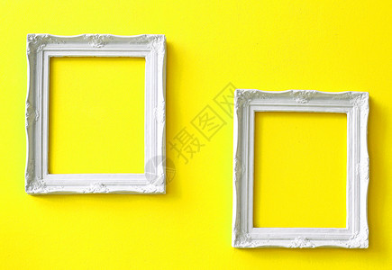 黄墙上两个白色的旧框背景图片