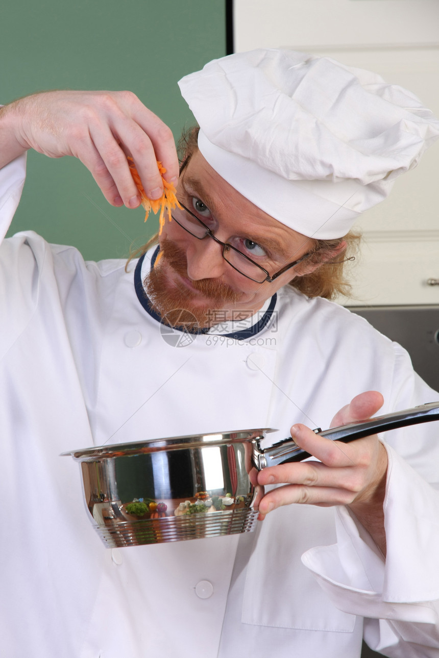 有趣的年轻厨师在锅里加胡萝卜衣服餐厅厨房白色职业美食烤箱帽子烹饪工作图片