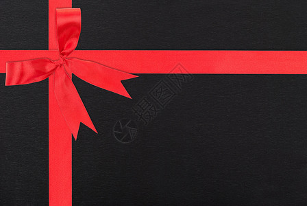 裹在黑纸上的红色带丝带和弓领礼盒背景图片
