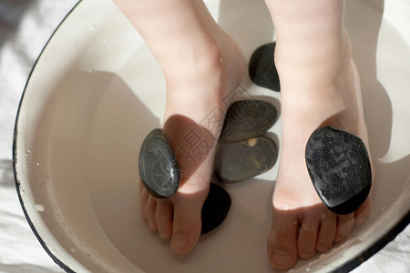 小孩脚用石头在洗脸盆里背景图片