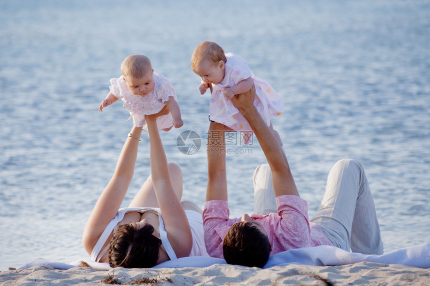 家庭在海滩上双胞胎孩子们育儿假期母性母亲新生儿父母拥抱女孩们图片