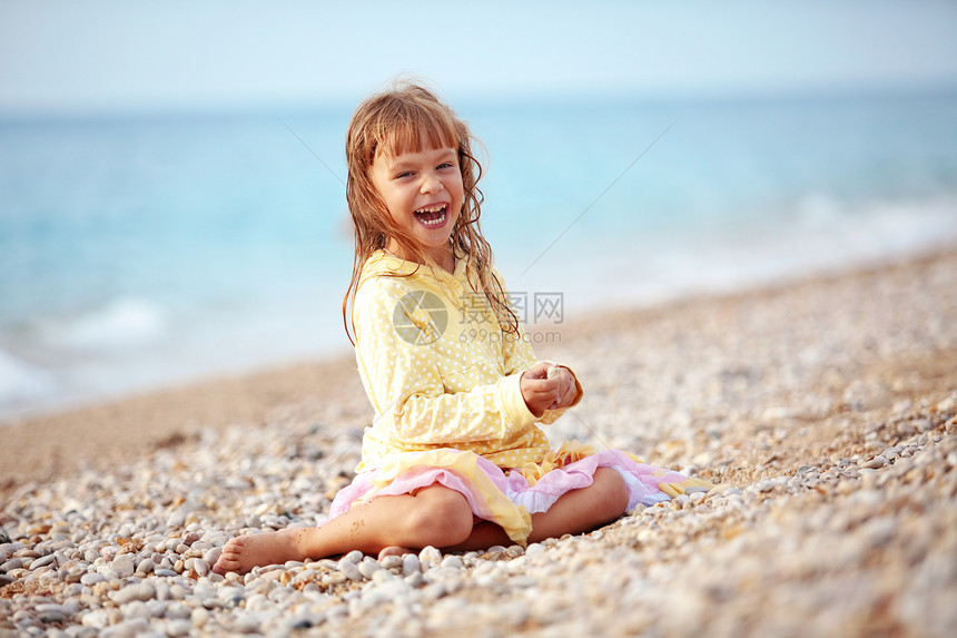 海滩上的孩子乐趣假期女儿女孩衣服育儿海洋赤脚卵石场景图片