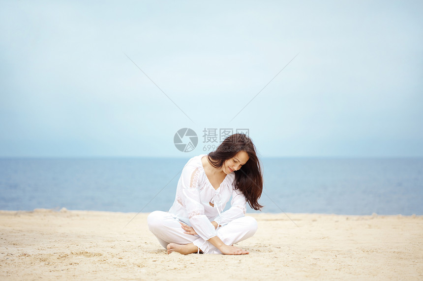 海滩上的女人头发自由天空女孩冒充闲暇休息女士蓝色假期图片